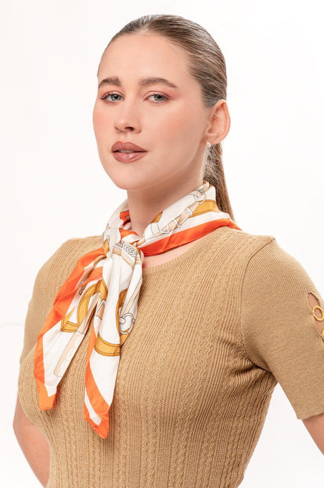 Mujer con pañuelo naranja y blanco con detalles dorados, suéter beige de manga corta con detalles en la manga