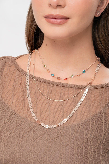 Collares dorados y coloridos sobre mujer con blusa marrón de encaje transparente